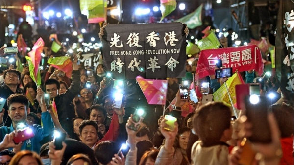 圖為來台觀選的香港「反送中」抗爭者十一日在民進黨中央黨部外，高舉及吶喊「光復香港，時代革命」口號。