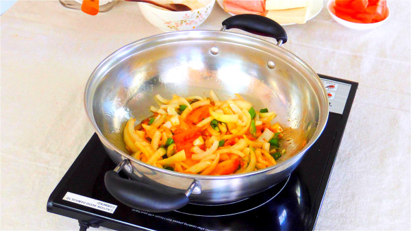 锅内放入洋葱丝、韩国泡菜和葱，炒香。