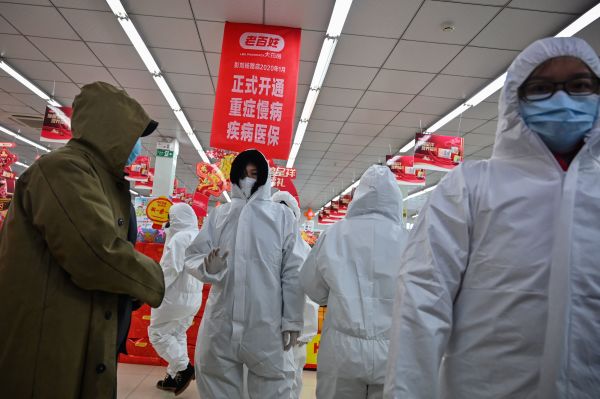 2020年1月25日，武汉戴着防护服和口罩的药房工作人员在为客户服务。