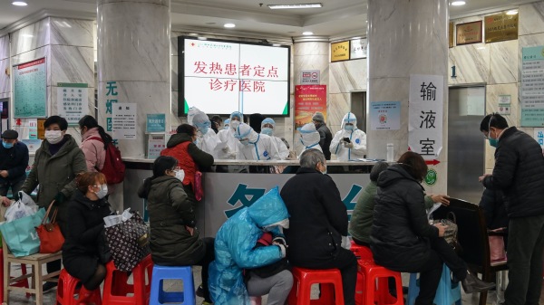 2020年1月24日，武漢市武漢市紅十字會醫院人們排隊等待醫治，醫務人員（背部）穿著防護服防止「中共肺炎」致命病毒的傳播