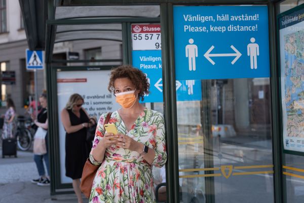 6月26日，瑞典，一名女子站在一块写有“保持安全社交距离”的牌子旁边