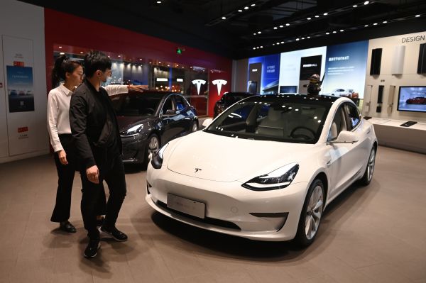 2020年10月21日，一名男子在北京一场车展上看一辆白色的特斯拉汽车