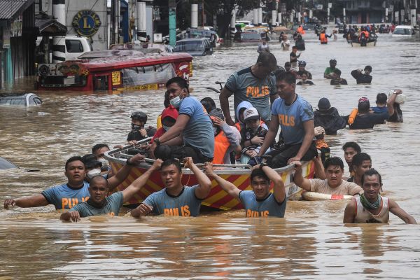 2020年11月12日，在馬尼拉郊區馬里基納市遭颱風襲擊後，救援人員拉著橡皮船載著居民穿過一條洪水氾濫的街道。