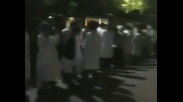 上海南汇中心医院的医生、护士都穿着白大褂排队等待核酸检测（图片来源：视频截图）