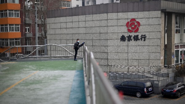 一名戴着口罩的男子于2020年2月13日在北京的一个立交桥上进行体育锻炼。（图片来源：STR/AFP/Getty Images）