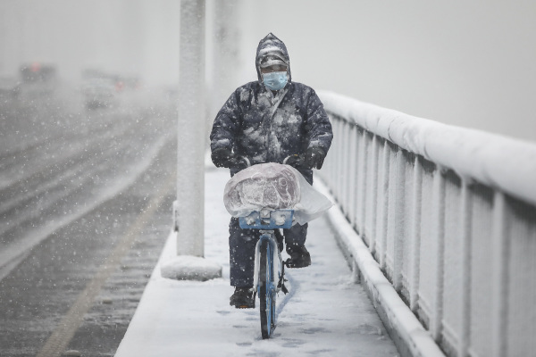 2020年2月15日，武汉封城期间，一名男子在雪中骑着自行车。