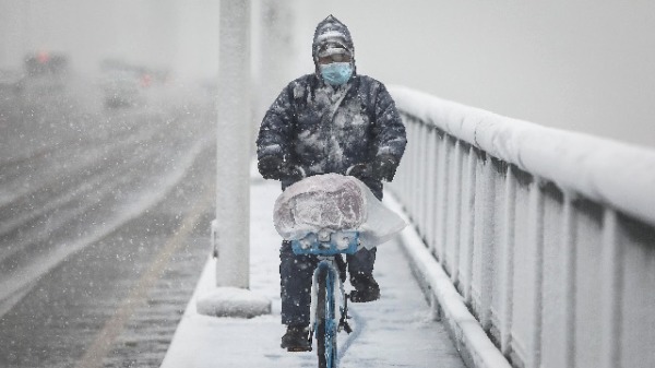 2月15日，武汉封城期间，一名男子在雪中骑着自行车。
