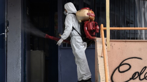 2020年2月27日，一名工人在希腊北部塞萨洛尼基的一所学校内喷洒消毒剂，以预防新型冠状病毒的传播。（图片来源：SAKIS MITROLIDIS/AFP/Getty Images）