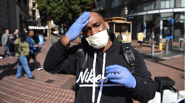 加州居民卡梅隆．南丁格爾（Cameron Nightingale）於2020年2月27日在舊金山行走時，調整了自己的口罩和手套，這是保護自己免受冠狀病毒感染的預防措施。（圖片來源：JOSH EDELSON/AFP/Getty Images）