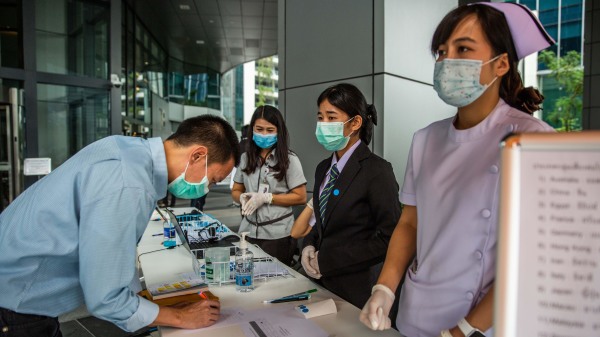 2020年2月28日，卫生人员在泰国曼谷在泰国证券交易所前检查戴着口罩的人。
