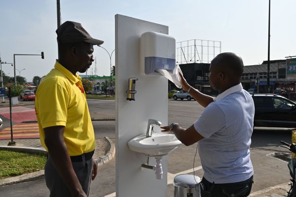 2020年3月19日，非洲科特迪瓦最大城市阿比让，一名男子在一家商店的入口处洗手。