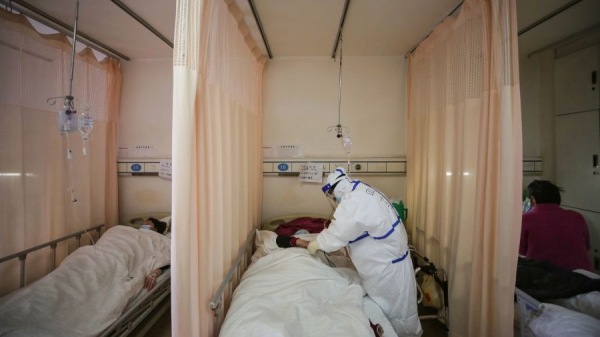 2020年3月11日，一名醫務人員在武漢市紅十字會醫院治療一名中共肺炎患者