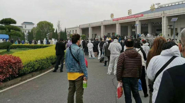在武漢一家殯儀館前，排隊等候領取親人骨灰的人們。