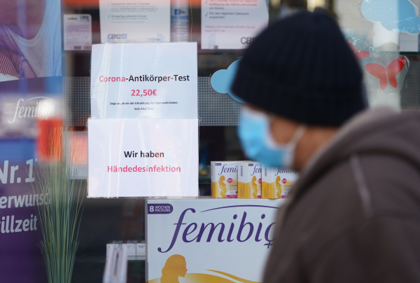 2020年4月9日，一個德國男子走過一家藥房門口，玻璃上的廣告提示藥店可以測試冠狀病毒抗體。
