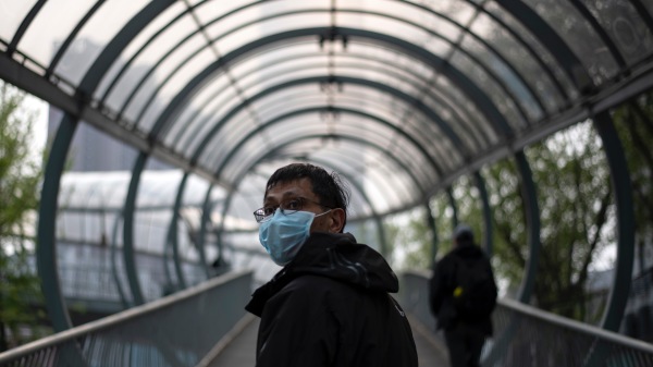 一名戴着口罩的男子于2020年4月3日在武汉市的一座天桥上行走。