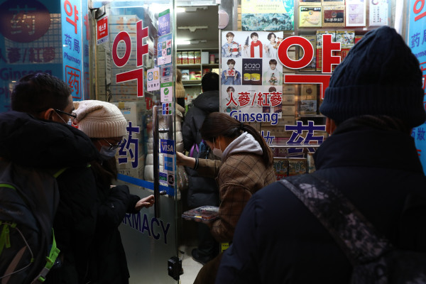 2020年1月31日，人们在首尔明洞购物街的一家药房购买口罩后离开。