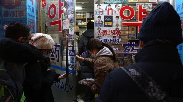 2020年1月31日，人们在首尔明洞购物街的一家药房购买口罩后离开。