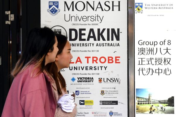 2020年6月10日，2个亚裔面孔的女子路过墨尔本中央商务区一处标有几所澳大利亚大学广告牌前。