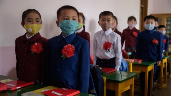 2020年6月3日，朝鲜的小学重新开放后，孩童戴口罩别着鲜红胸花回到教室上课。