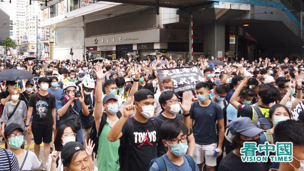 2020年7月1日，数以万计港人上街反对港版国安法，有市民展示“光复香港 时代革命”标语。（图片来源：庞大卫/看中国）