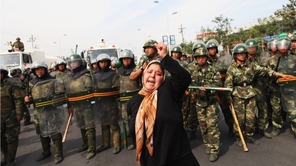 新疆一名维吾尔妇女站在警察前面抗争。（图片来源：Photo by Guang Niu/Getty Images）