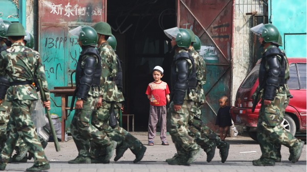 新疆乌鲁木齐一名维吾尔小孩看着警察走过。（图片来源：Photo by Guang Niu/Getty Images）
