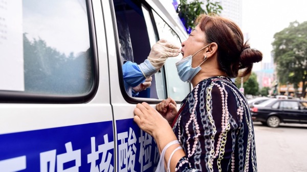 2020年7月29日，一名卫生工作者在辽宁省沈阳市的阶梯测试车上给一名居民进行病毒测试。