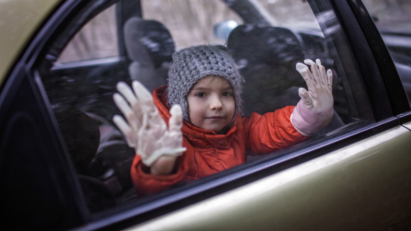 在汽车中带着塑胶手套预防COVID-19病毒接触的儿童