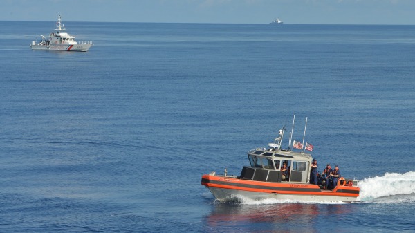 2019年5月14日，菲律宾海岸警卫队（左）和美国拦截舰艇在南海士嘉堡浅滩附近的联合搜救演习中，一艘中国海岸警卫队船（后右）在远处监测。（图片来源： TED ALJIBE/AFP via Getty Images）