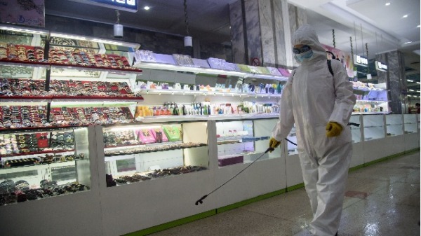 12月28日，在平壤第一百货公司开业前，一名卫生工作者在喷洒消毒剂