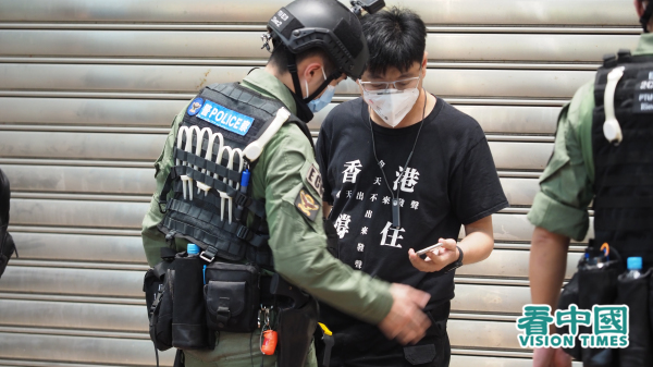 外媒报导港警将民主派被捕人的手机和电脑“送中”破解。图为港警检查示威者的手机。（图片来源：李天正/看中国）