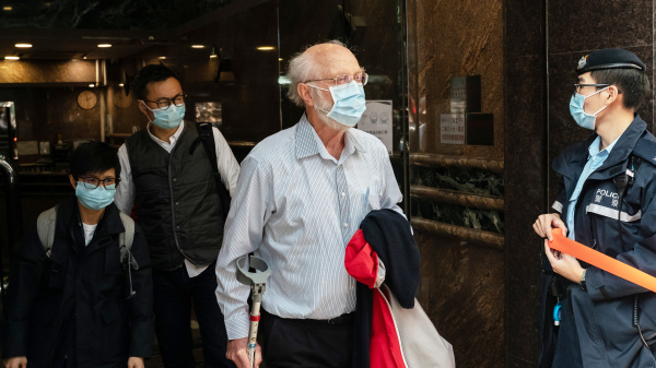 1月6日，港警國安處出動過千警力大舉搜捕53人，其中包括美籍人權律師關尚義（John Clancey），他持枴杖步上警車前，勉勵香港人為民主和人權而努力。（圖片來源：Anthony Kwan/Getty Images）