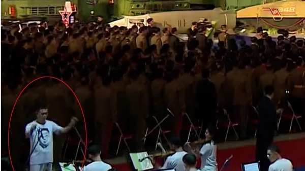 朝鲜乐团的指挥身上穿着印有金正恩照片之白色T恤。