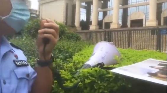一名警察用扩音喇叭在广东省高级法院外维权。