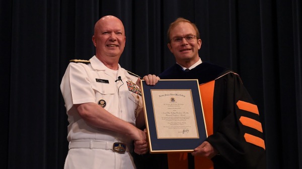 美国海军战争学院（NWC）院长哈雷上将（左）向本文作者埃里克森教授颁发了文职教师研究卓越奖。