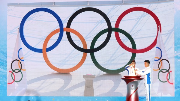 2021年10月20日，在中國北京舉行的北京2022年奧運聖火歡迎儀式上，火炬手將奧運聖火從安全燈籠轉移到火炬上。（圖片來源：Lintao Zhang/Getty Images)