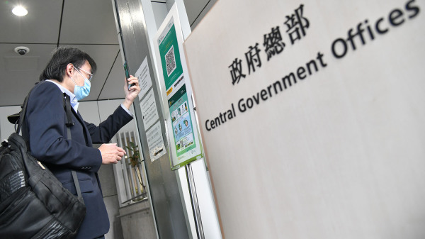 有港媒表示，政府正研究强制港人安装手机程式“安心出行”，并上载行踪到政府服务器，才能免检疫返大陆。图为市民在进入政府总部时使用“安心出行”。（图片来源：香港政府新闻处）