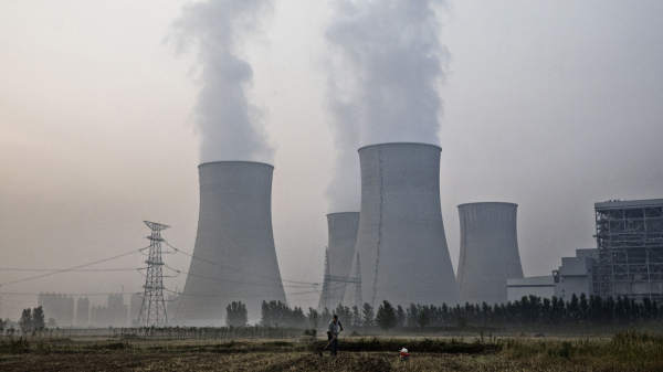 2017年6月15日，一位農民在安徽淮南市的一家國有燃煤發電廠旁邊的田地裡工作。