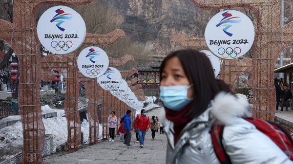 在中國北京舉行的冰雪節上，人們戴著防護口罩走在2022年北京冬奧會的標誌前。