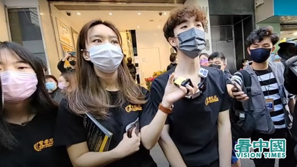 香港学生组织“贤学思政”摆街站呼吁公众杯葛“安心出行”应用程式。左一为朱慧盈，右二王逸战。（图片来源：视频截图/看中国YouTube）