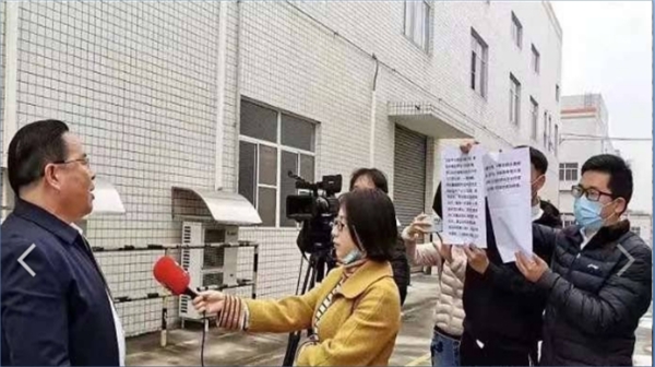 18日，四川内江市发改委官员郑敏在接受电视采访时，看其下属在镜头后手举的纸稿念稿（图片来源：微博）