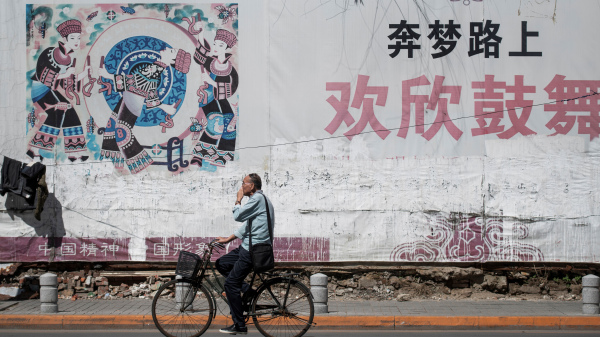 2018年5月29日，辽宁丹东的一位路人骑自行车经过一副中国梦的标语牌。