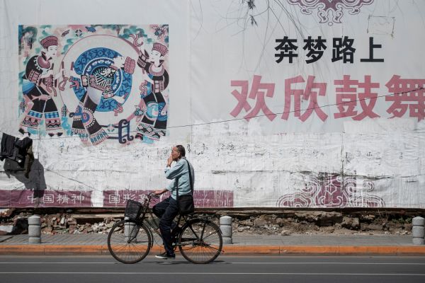 2018年5月29日，遼寧丹東的一位路人騎自行車經過一副中國夢的標語牌。（圖片來源：FRED DUFOURAFP via Getty Images）