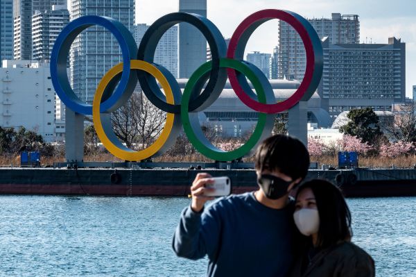 2021年2月24日，一对情侣在东京台场海滨展出的奥运五环前摆姿势的照片。