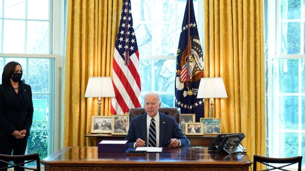 2021年3月11日，在白宫椭圆形办公室拜登准备签署《美国救援计划》法案，旁边站立者为贺锦丽。（图片来源：MANDEL NGAN/AFP via Getty Images）
