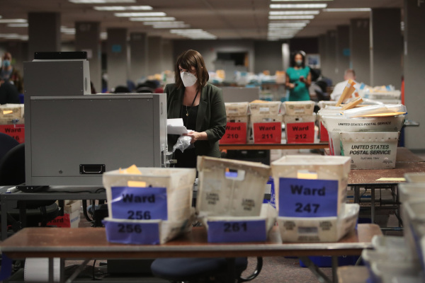 图为2020年11月4日，威斯康星州密尔沃基市选举委员会执行主任从投票机里收集缺席选票（邮寄选票）的计票结果。（图片来源： Scott Olson/Getty Images）