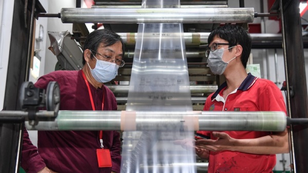 铭安科技董事长黄建铭（左）检视刚成形的生物可分 解塑胶膜，准备要逐步扩大产能，抢攻绿金市场。