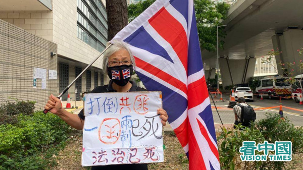 王婆婆举英国国旗和自制海报到场声援九名民主派人士。（图片来源：王文君/看中国）