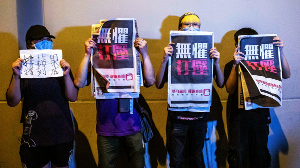 图为2020年8月，港府以国安法名义逮捕壹传媒创办人黎智英后，民众手举苹果日报在旺角警署外声援。（图片来源：Getty Images）