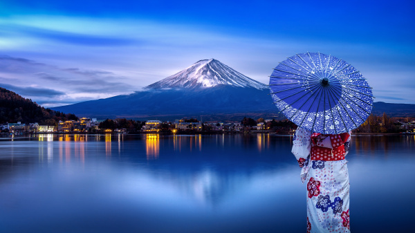 穿着和服的日本女人撑伞看着富士山。